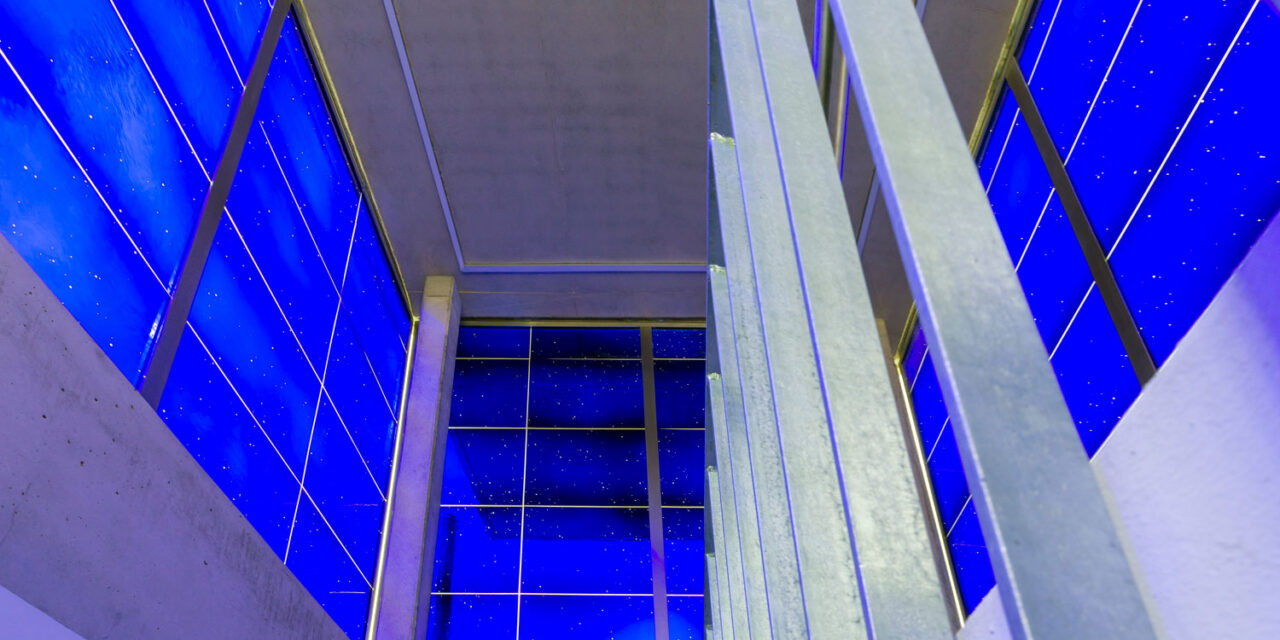 A stairwell enclosed in blue mouth-blown glass.